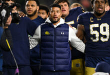 Notre Dame Fighting Irish head coach Marcus Freeman locks arms with his players.