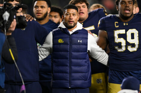 Notre Dame Fighting Irish head coach Marcus Freeman locks arms with his players.
