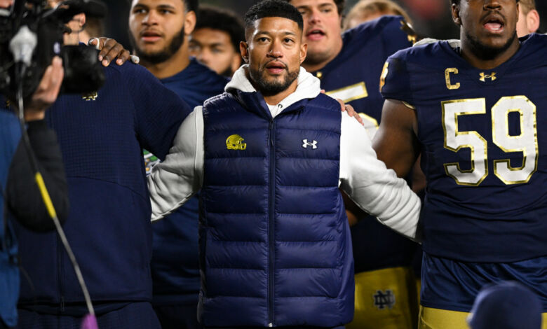 Notre Dame Fighting Irish head coach Marcus Freeman locks arms with his players.
